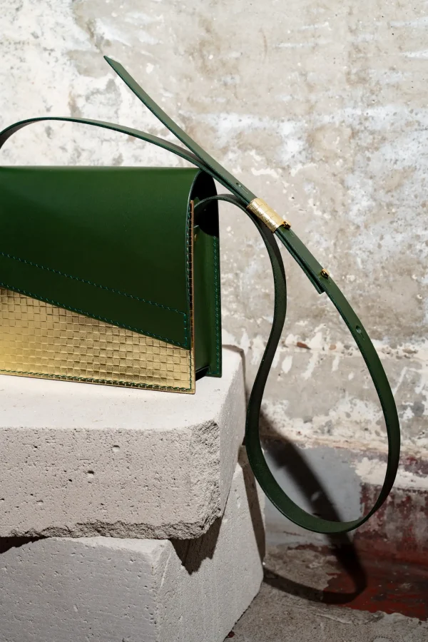 Detail van de groene Reese W. handtas met gouden front in geweven structuur, groene riem en gouden passant.