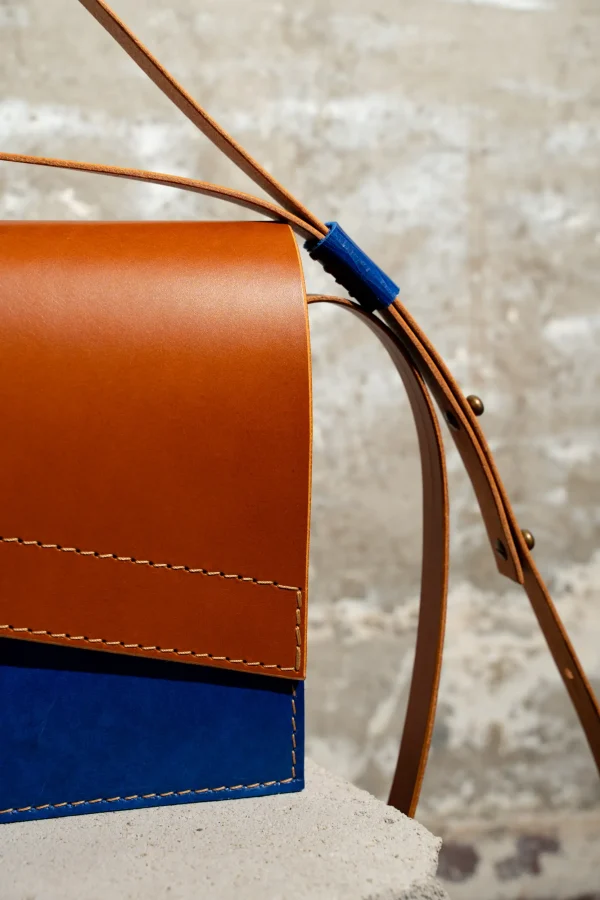 Detail van de cognac Reese W. handtas met kobaltblauw front, cognac riem en kobaltblauwe passant.