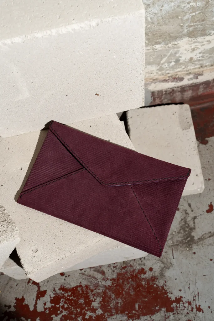 Plum of donkerpaarse Billie E. enveloppetas met gestreepte structuur in het leder, liggend.