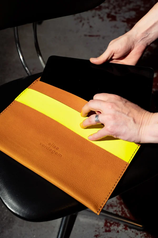 De Kate W. tablethoes in cognac leder met fluogele sluitriem, waar iPad wordt ingeschoven.