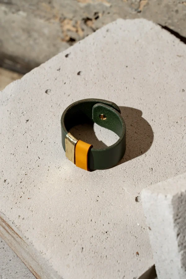 The Combo armband in groen leder met afneembare contrastkleuren in okergeel en goud structuur. De armband sluit met een geweerknoop.