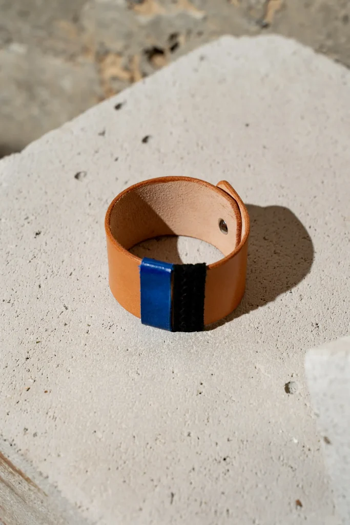 The Combo armband in naturel leder met afneembare contrastkleuren in kobaltblauw en zwart structuur. De armband sluit met een geweerknoop.