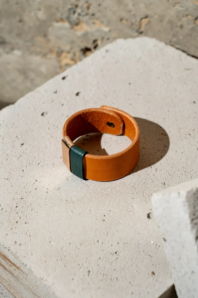 The Combo armband in cognac leder met afneembare contrastkleuren in petrol en rosé métallic. De armband sluit met een geweerknoop.