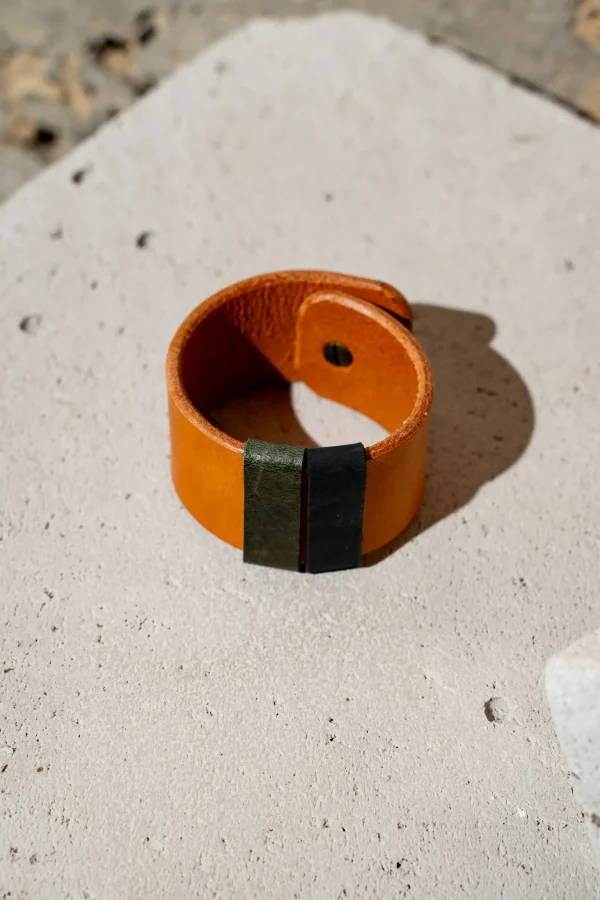 The Combo armband in cognac leder met afneembare contrastkleuren in groen en zwart. De armband sluit met een geweerknoop.