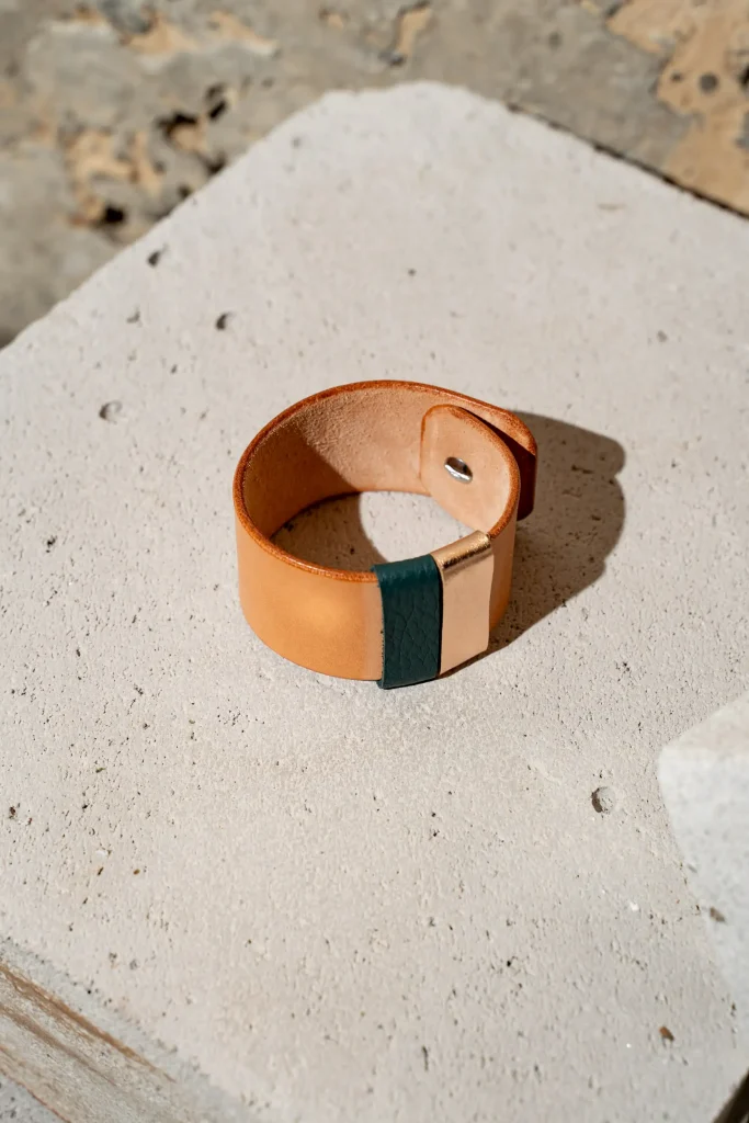 The Combo armband in naturel leder met afneembare contrastkleuren in petrol en rosé métallic en sluiting met een geweerknoop.