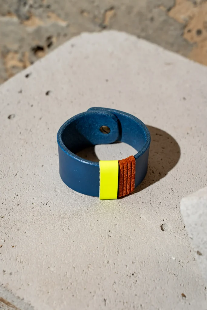 The Combo armband in kobaltblauw leder met afneembare contrastkleuren in fluogeel en rust. De armband sluit met een geweerknoop.