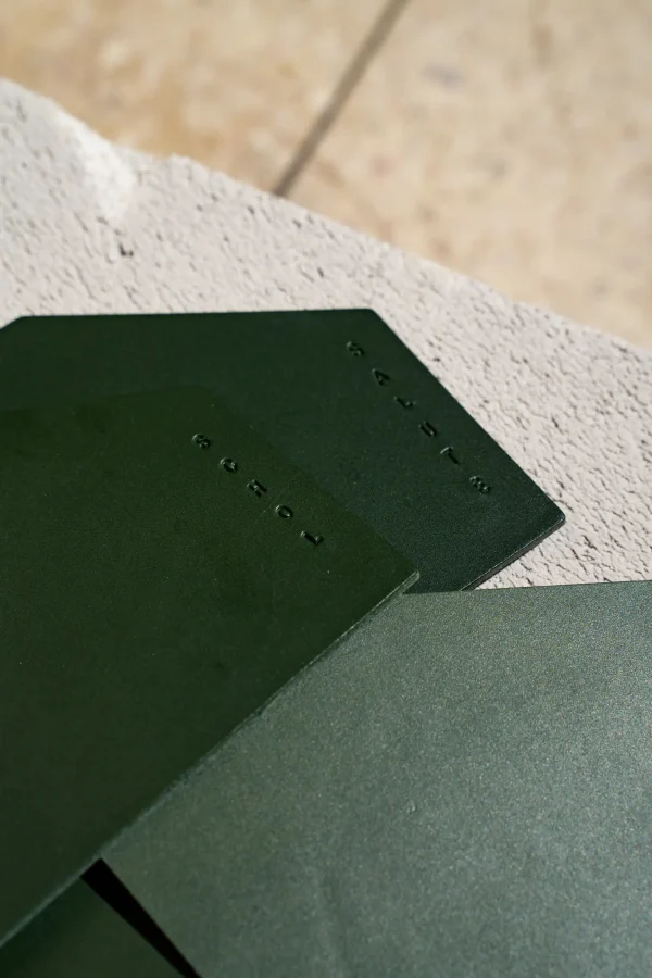 Detail van de asymmetrische groene lederen coasters met de teksten 'schol' en 'salute' op.